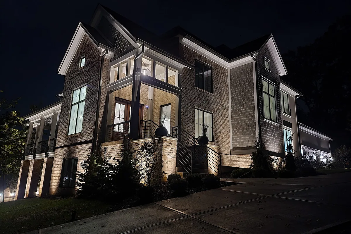 After: the same home transformed with warm architectural and landscape uplighting by USA Lighting