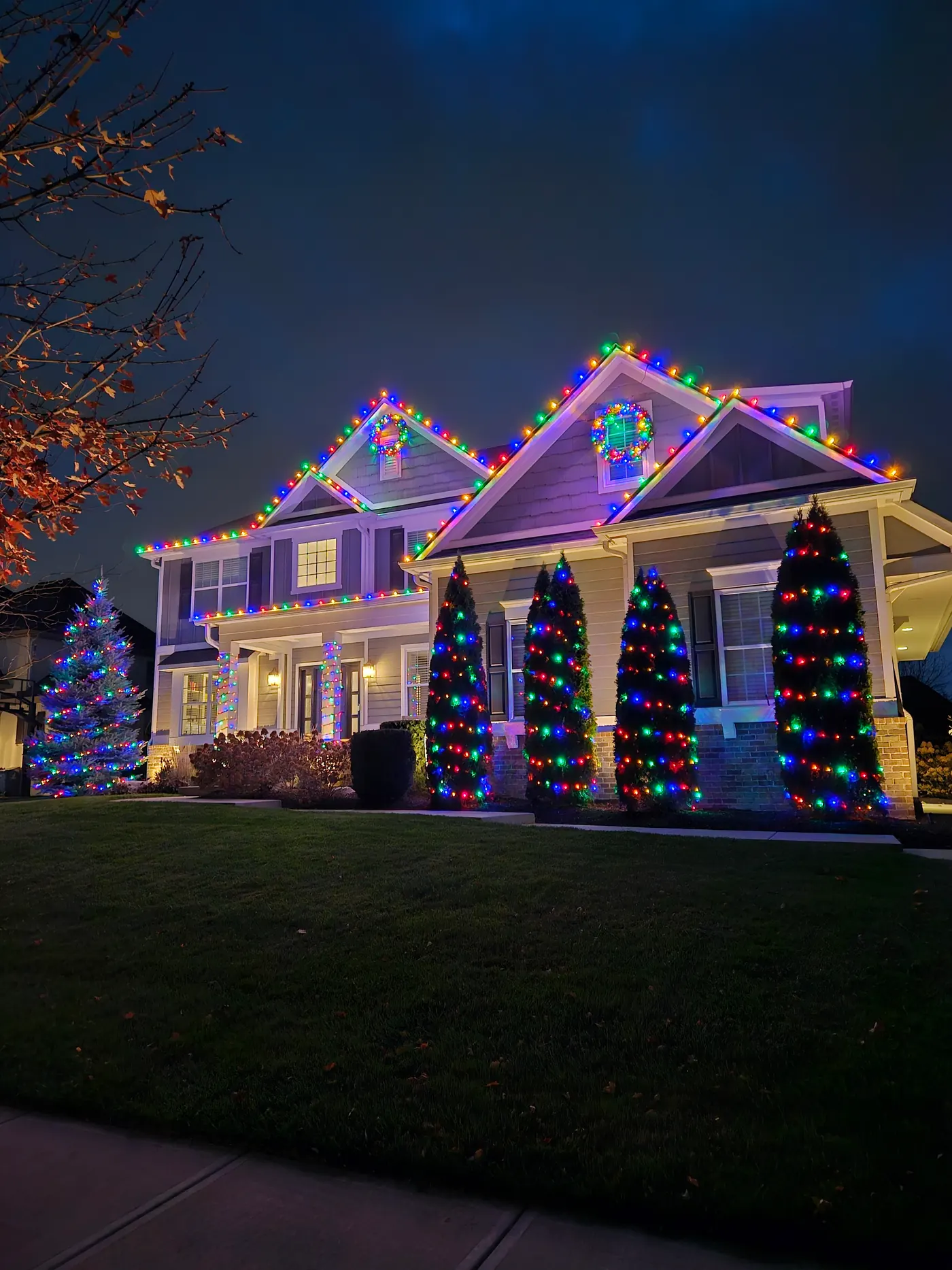 Elegant warm-white Christmas lighting outlining the rooflines of a large home at night