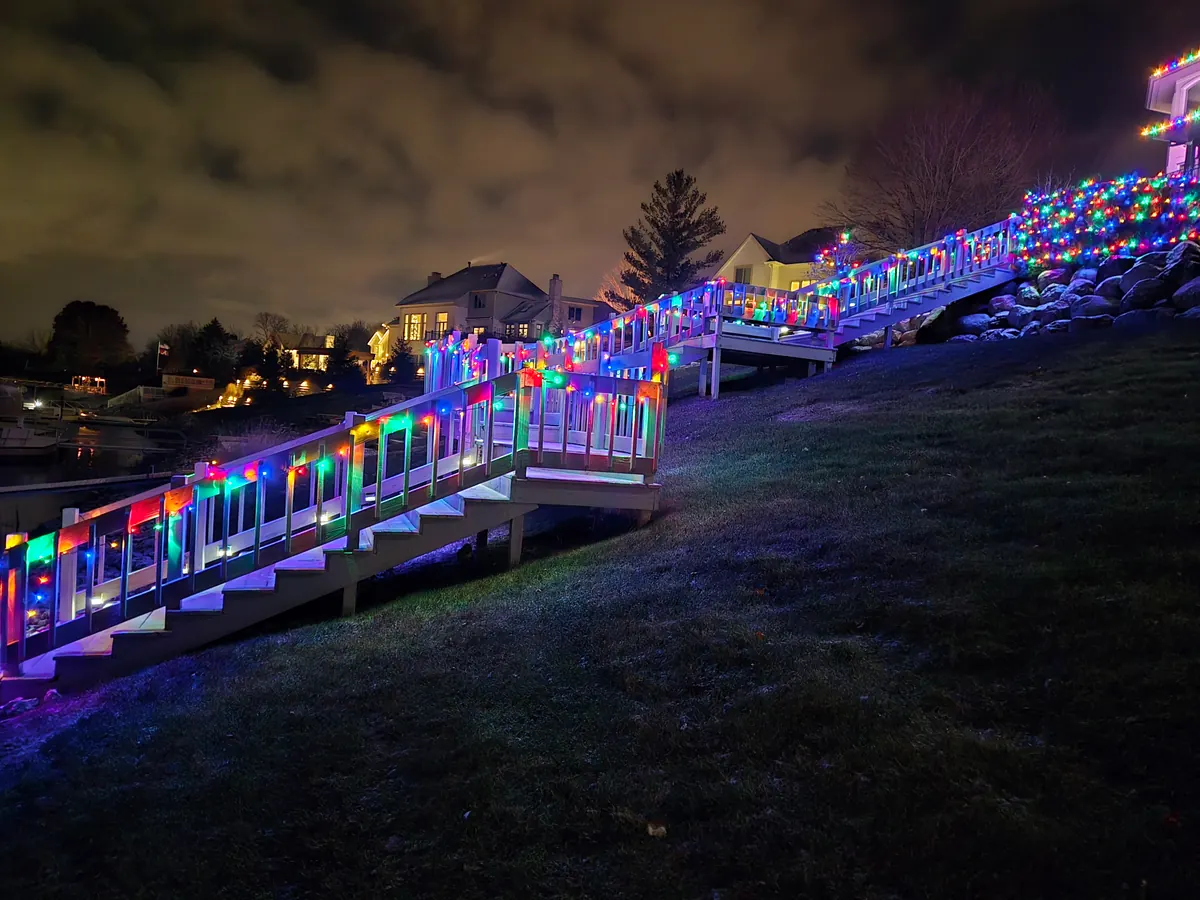 Multicolor Christmas lights wrapped around deck railings in a dense pattern