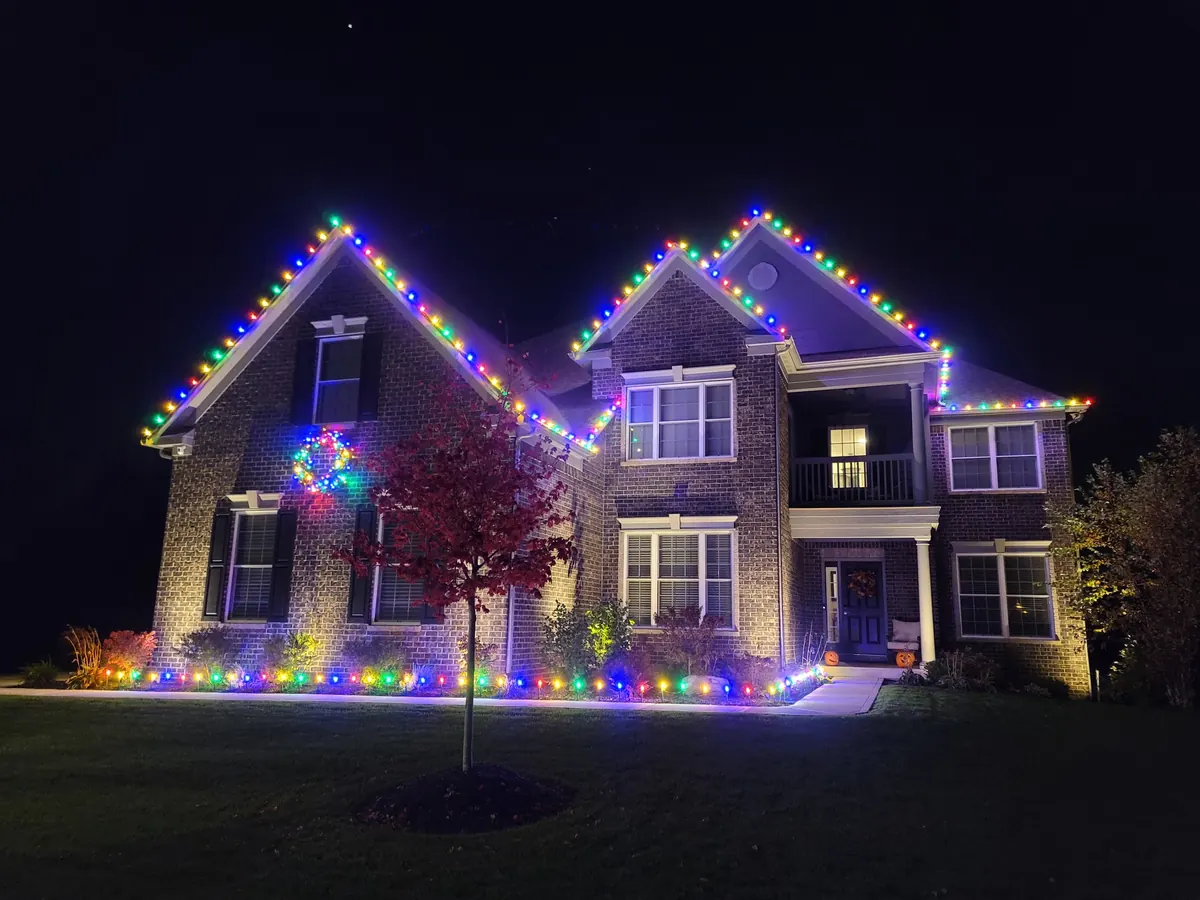 Two-story brick home with multicolor lights covering the entire front facade