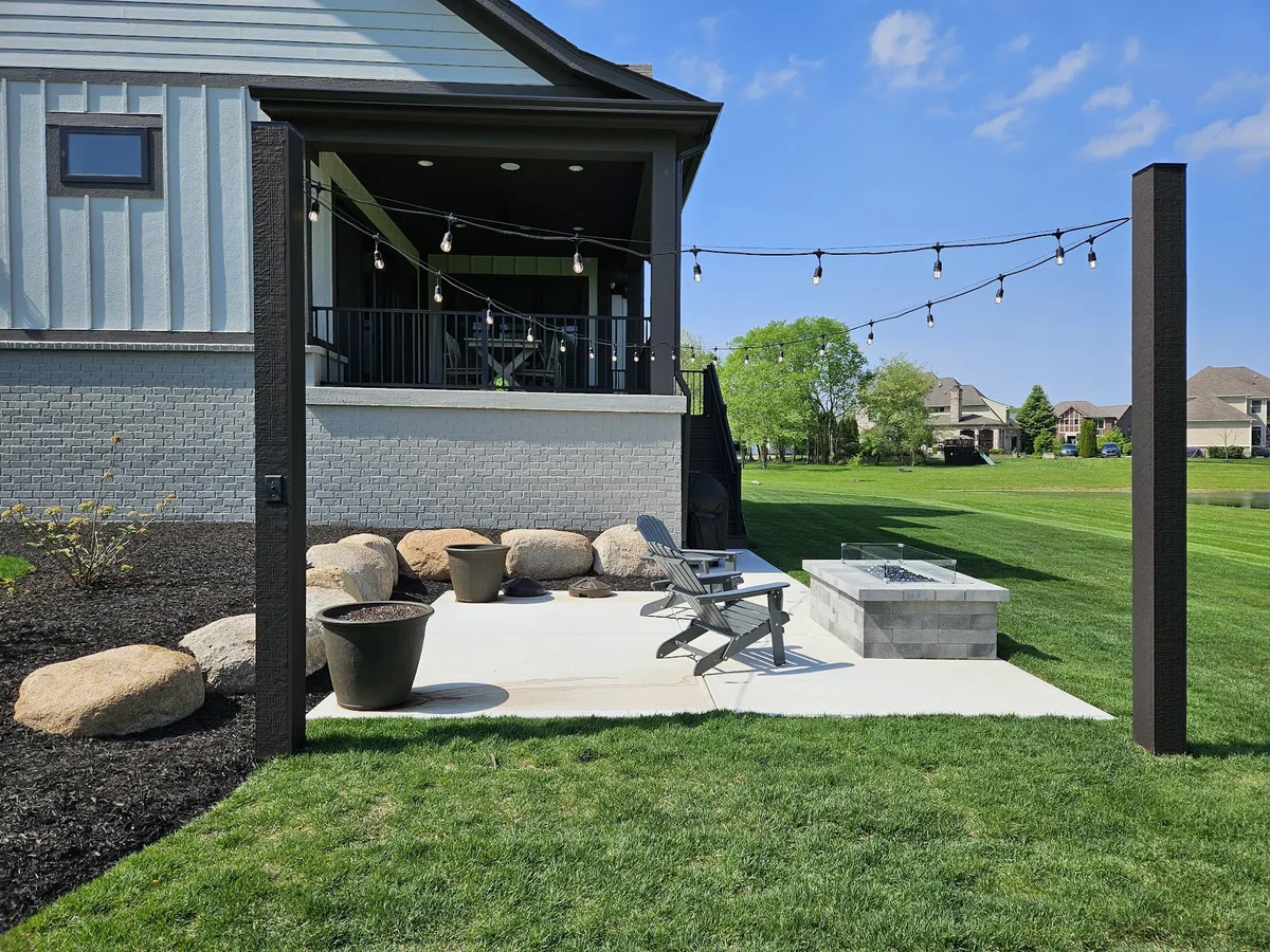Backyard patio with a fire pit and bistro string lights strung from a covered porch