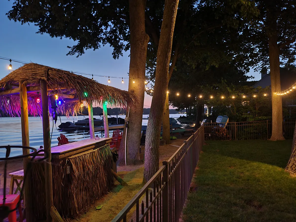 Warm bistro string lights over an outdoor living space at dusk